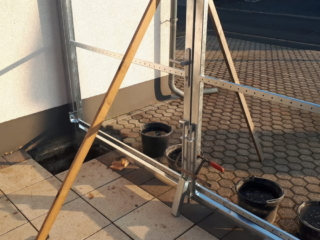 Einbau: Pfosten mit Bandlaschen in Öffnungsrichtung in die Löcher stellen Einbau: Pfosten mit Bandlaschen in Öffnungsrichtung in die Löcher stellen