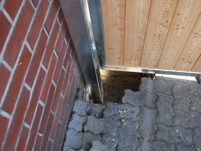 Detail: Loch zum Einbetonieren eines Pfostens (Einfahrtstor mit Holzverbretterung)